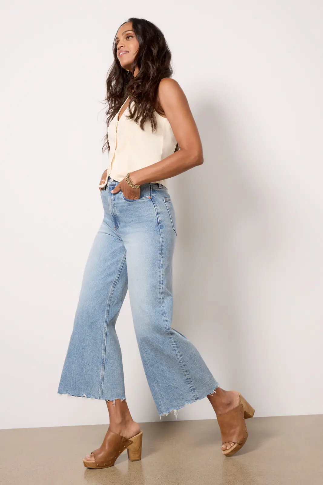 Chic woman modeling flared premium denim jeans paired with a cream top, showcasing the exquisite style and craftsmanship that justify why premium denim is so expensive.