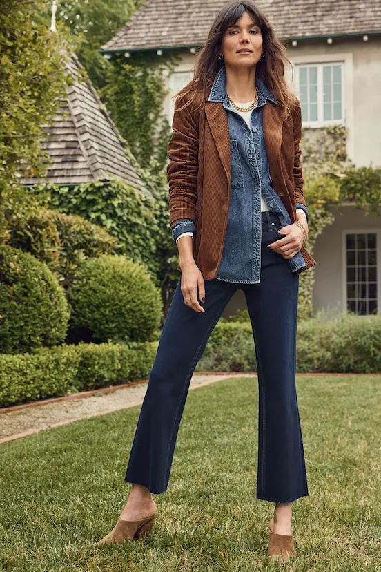 A woman layering a denim shirt with a corduroy blazer and denim jeans, demonstrating how to wear denim-on-denim with a polished, layered fall outfit.