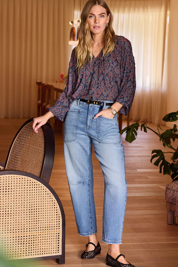 Spring 2025 trends in denim featuring utility-style wide-leg jeans with patch pockets, paired with a floral print blouse and black mary jane flats